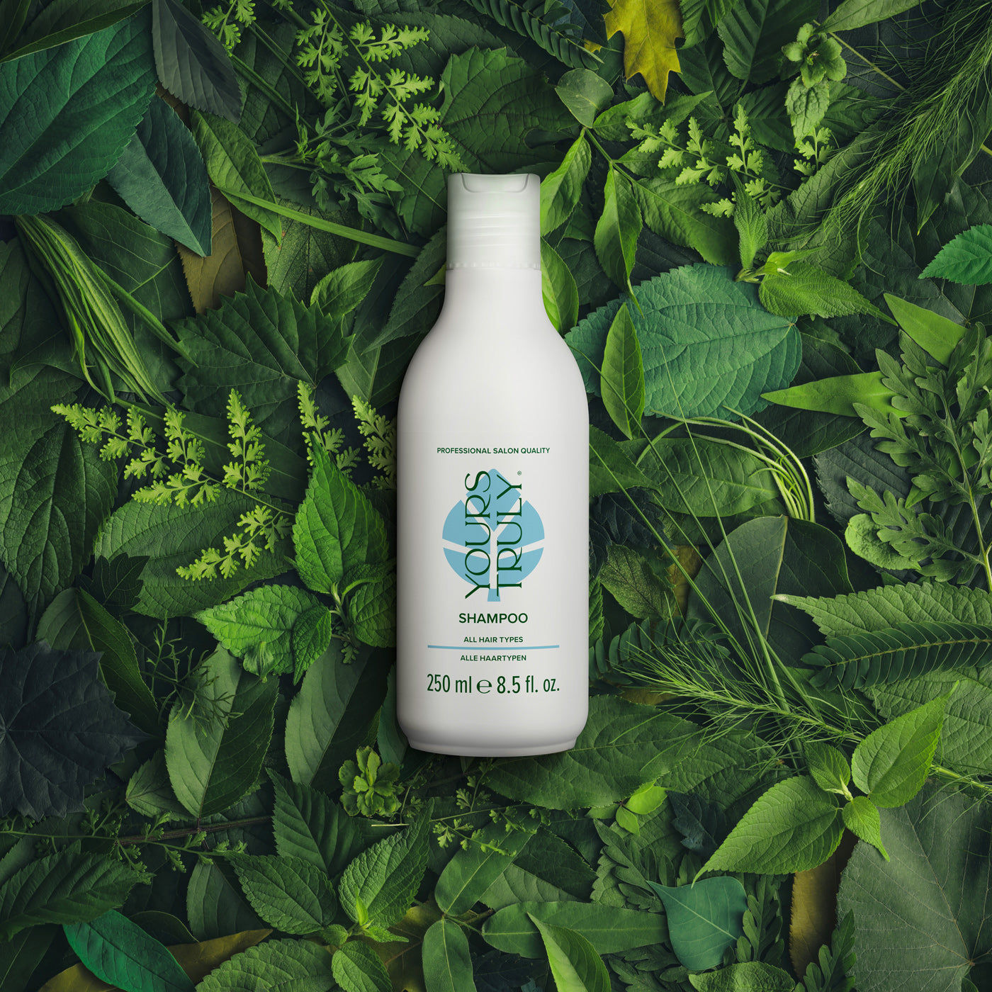 yours-truly-shampoo-flasche-für-alle-haartypen-auf-grünem-blätterhintergrund