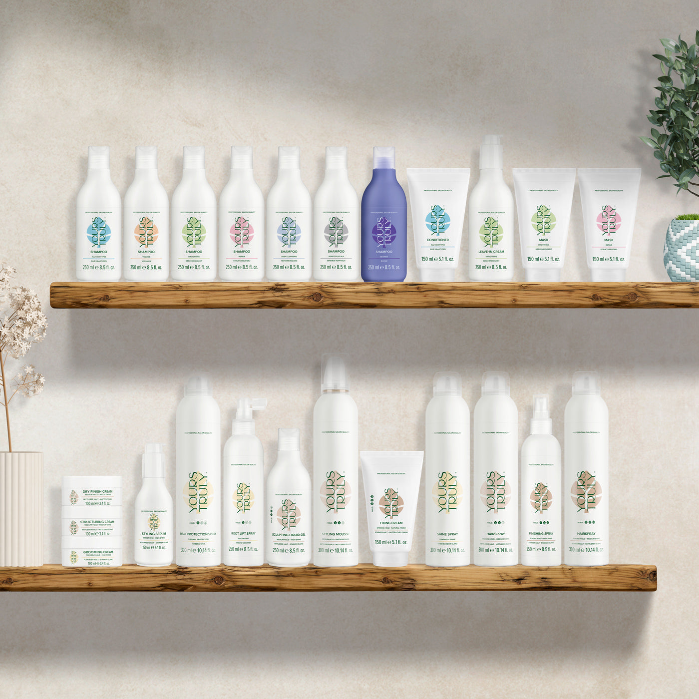 zwei-holzregale-mit-vielen-yours-truly-haarpflegeprodukten-in-weißen-und-einigen-farbigen-flaschen-und-tuben-gegen-helle-wand-dekoriert-mit-pflanzen